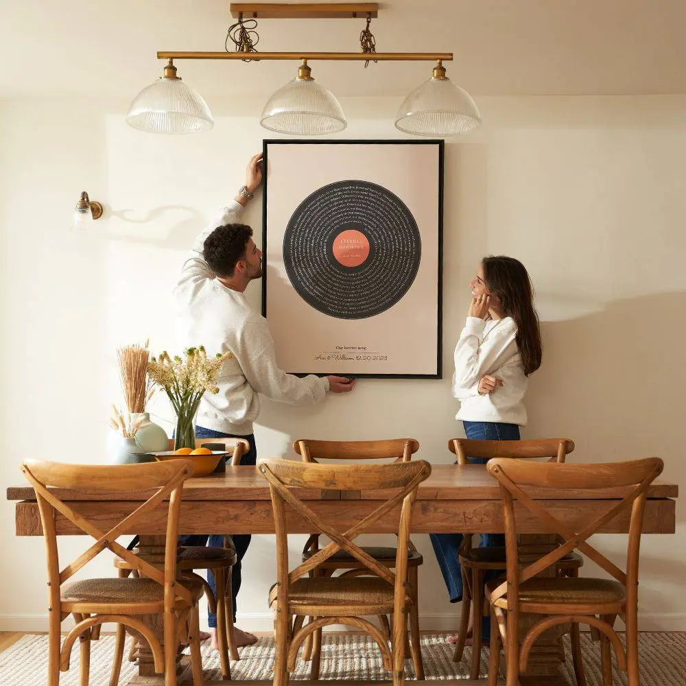 Couple hanging a framed custom song lyrics print on the wall